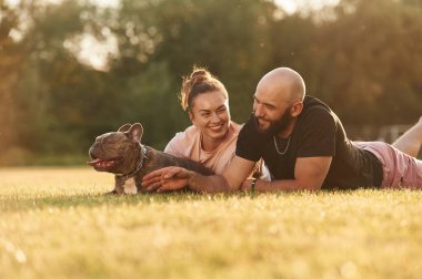 Sakin ol, yere yat. Erkek ve kadın sahada köpekle birlikteler..