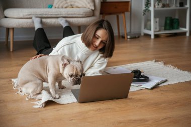 Laptop kullanıyorum. Genç kadın köpeğiyle evde..