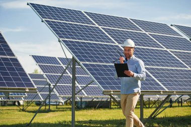 Telsiz kullanarak ve not defteri tutarak. Gündüz vakti fotovoltaik güneş panelleri olan bir mühendis..