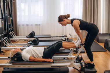 Bacak egzersizi. Kadın eğitmen yaşlı kadına yardım ediyor..