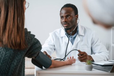 Müşteri hizmetleri. Bir doktor genç bir kadının kan basıncını ölçer..