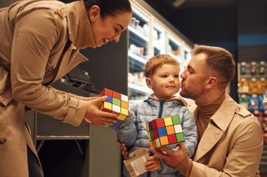 Ailesi oyuncakçıda, ellerinde Rubik küpü var..