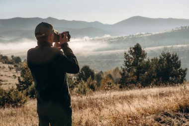 Kameralı adam ayakta duruyor, Karpat dağlarının görkemli manzarası.