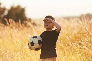 Futbol topunu tutuyorum. Küçük çocuk yazın dışarıda eğleniyor..