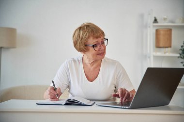 Laptop kullanıyorum. Yaşlı yaşlı kadın evde, oturma odasında..