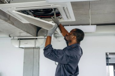 Havalandırmayı tamir ediyorum. Tamirci modern ofiste kapalı bir yerde..