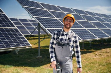 Çalışmaya hazır, matkapla. Gündüz vakti fotovoltaik güneş panelleri olan bir mühendis..