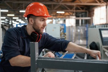 Makinelerle çalışmak. Fabrika işçisi kasketli bir şekilde içeride..