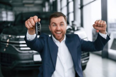 Otomobilin yeni sahibi çok mutlu. Bir iş adamı araba galerisinde..