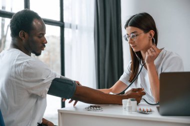 Sağlık sigortası gebeliği. Kadın doktor bir erkeğin kan basıncını ölçer..