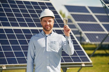 Elde ampul. Gündüz vakti fotovoltaik güneş panelleri olan bir mühendis..