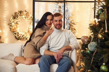 Oturuyor ve gülümsüyor. Çift içeride yeni yılı kutluyor..