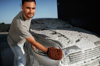 Otomobili yıkama işlemi. Adam dışarıda arabasıyla bekliyor..