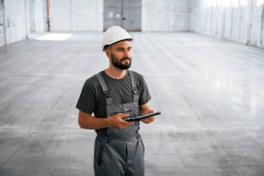 Önden bak, elinde dijital tabletle. Erkek işçi boş depoda..