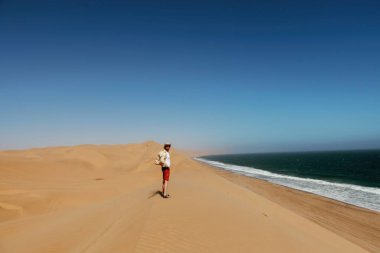 Turist deniz kenarındaki kumda yürüyor..