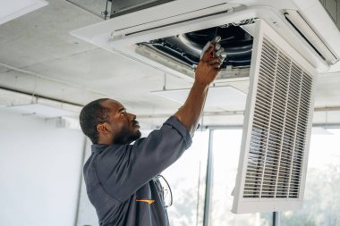 Havalandırma tavanda, tamir ediliyor. Tamirci modern ofiste kapalı bir yerde..