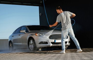 Otomobil yıkama, adam dışarıda arabasıyla bekliyor..