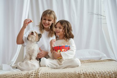 Patlamış mısırla beslenen köpek. Anne ve kızı evde birlikteler..