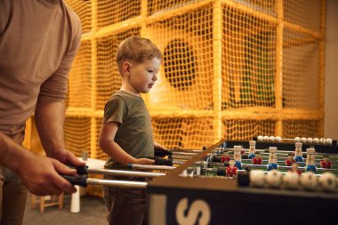 Çocuk oyun odası. Baba ve oğul içeride masa futbolu oynuyorlar..
