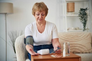 Kan basıncını ölçer. Yaşlı yaşlı kadın evde, oturma odasında..