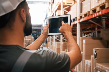 Dijital tableti kullanarak. Foreman depoda, kargo dağıtım işinde..