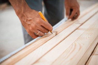 Kestiği yerleri ve odun parçalarını ölçen bir adamın ellerine yakından bakın..