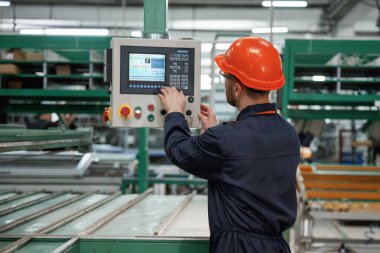 Makine ayarları ayarlanıyor, çalışıyor. Fabrika işçisi kasketli bir şekilde içeride..