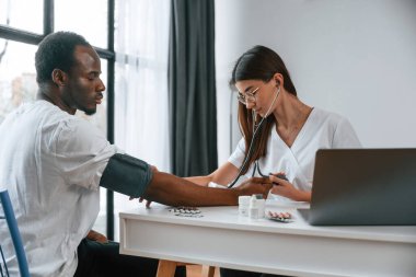 Sağlık sigortası gebeliği. Kadın doktor bir erkeğin kan basıncını ölçer..