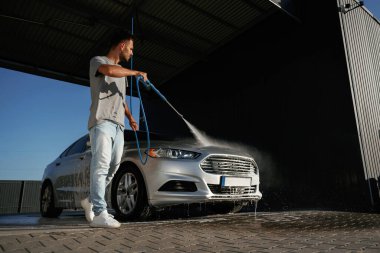 Etrafta dolaşmak ve otomobili yıkamak. Adam dışarıda arabasıyla bekliyor..