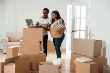 Laptop kullanan kablosuz cihaz. Afrikalı Amerikalı çift yeni eve taşınıyor..