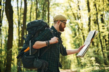 Büyük kağıt harita. Sakallı adam gündüz vakti ormandadır..