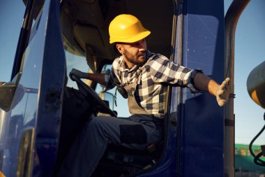 İnşaat işçisi kamyon kulübesinde oturuyor..