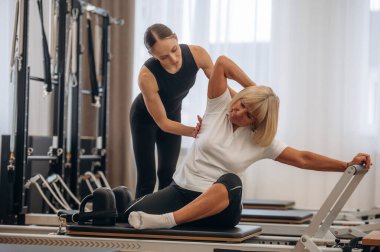 Sırt egzersizi. Kadın eğitmen yaşlı kadına yardım ediyor..