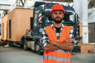 Kollarını kavuşturmuş duruyorsun. Ahşap depoda sanayi işçisi..