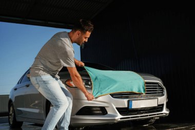 Kumaş, otomobili temizlemek. Adam dışarıda arabasıyla bekliyor..