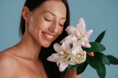 Yumuşak bir his, zambak çiçekleri tutuyor. Genç kadın stüdyoda arka planda..