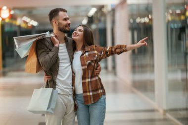 Elimle bir şey gösteriyorum. Genç çift süpermarkette beraberler..