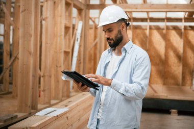 Dijital tablet kontrol altında. Ahşap depoda sanayi işçisi..