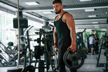 Ağırlık ellerde. Güçlü kaslı adam spor salonunda çalışıyor..