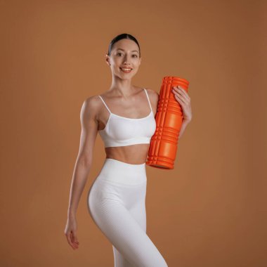 Kahverengi arka plana karşı. Güzel fitness kadını stüdyoda..