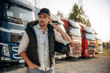 Şapkalı manken poz veriyor. Kamyon şoförü açık havada nakliye aracının yanında..