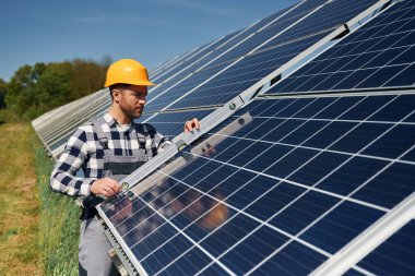 Dengeleyiciyi kullanarak. Gündüz vakti fotovoltaik güneş panelleri olan bir mühendis..