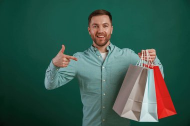 Alışverişten sonra, çantaları tutarken. Adam stüdyoda arka planda duruyor..