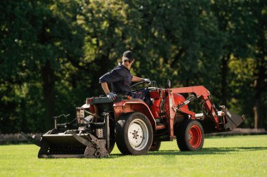 Otururken araba kullanmak. İnsan, çim biçme makinesi ve havacılık ekipmanlarıyla birlikte arazi aracında..