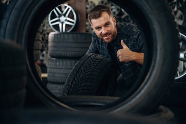 Gülümseme, pozitif yüz ifadesi, el hareketi. Tekerlekleri ve tekerlekleri olan tamirci var..