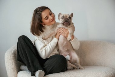 Ön manzara, küçük kanepede oturmak. Genç kadın köpeğiyle evde..
