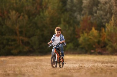Ata binmek, eğlenmek. Tatlı çocuk bisikletiyle sahada..