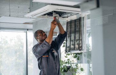 Yukarıda, havalandırmayı tamir ediyor. Tamirci modern ofiste kapalı bir yerde..