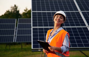 Üniformalı kadın işçi mühendisi güneş panellerinin yakınında..