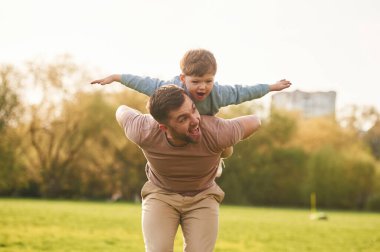 İnsanın omuzlarında otururken. Mutlu baba ve oğul yazın sahada eğleniyorlar..